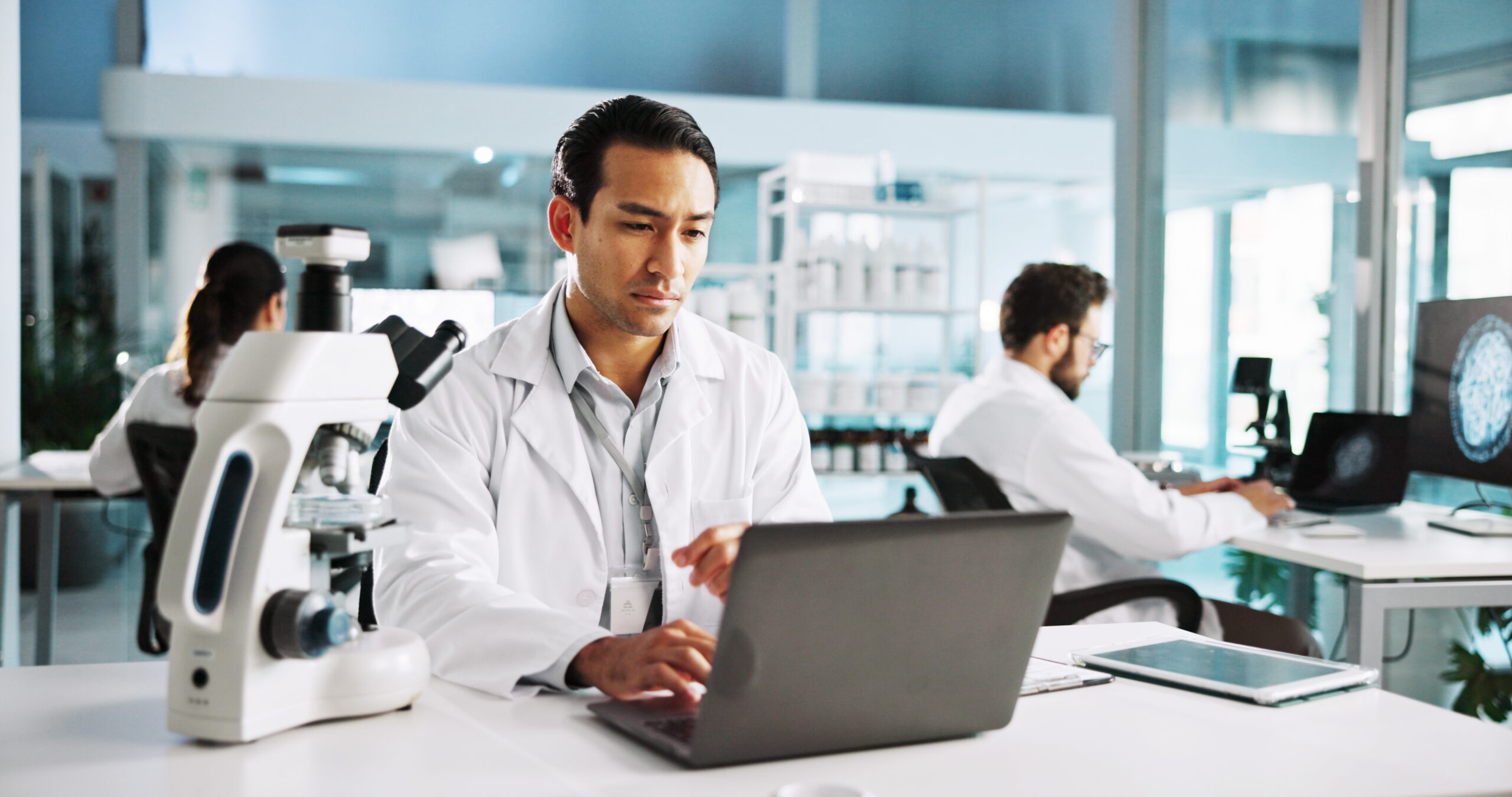 Laptop, science and study with man in laboratory for healthcare, medical or pharmaceutical innovation. Computer microscope and online research with scientist in clinical trial for development